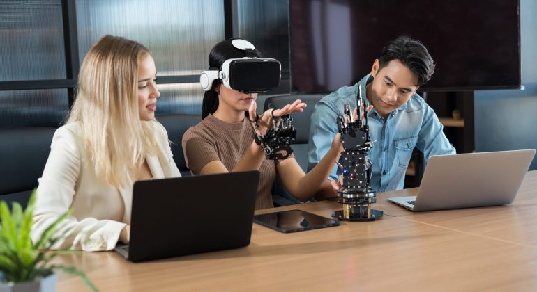 Male and female engineer working with vr glasses control AI robot arm system in workshop. Male engineer using laptop computer for training Programmable logic controller robotics arm system project